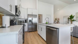 Une cuisine moderne avec des meubles blancs, des appareils en acier inoxydable et un îlot central.