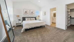 Une chambre à coucher avec un grand lit, une table de chevet, une commode et un placard.