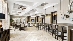 A spacious kitchen with a long bar area, modern ceiling design, and a dining area with chairs and a table. - 6BR Villa Oasis: Private Pool & Spa - Solterra Retreat (Davenport)