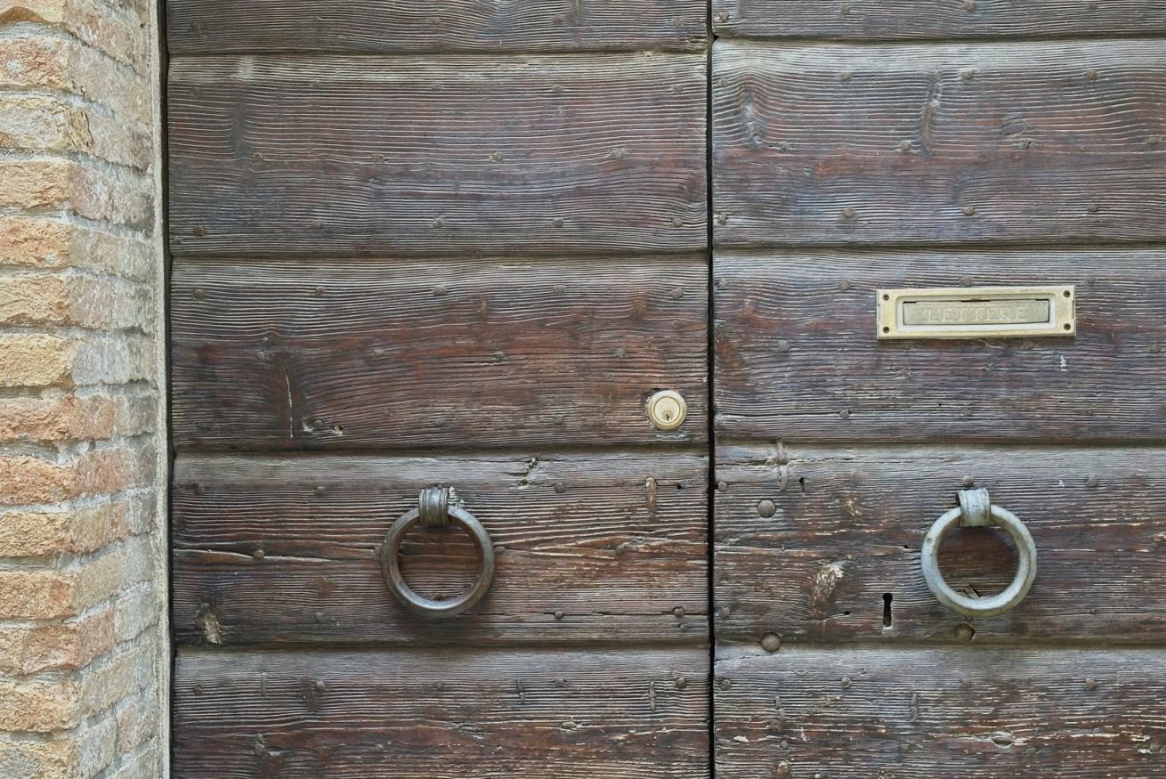 A wooden door with two metal rings and a brass plate.