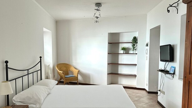 A bedroom with a bed, a chair, a TV, and a shelf with plants. - S296 - Sirolo, studio flat in the center with sea view (Sirolo)
