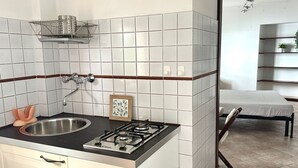 A kitchen with a sink, stove, and a small shelf with a plant. - S296 - Sirolo, studio flat in the center with sea view (Sirolo)