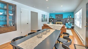 Una sala de estar moderna con comedor, chimenea y televisor montado en la pared.