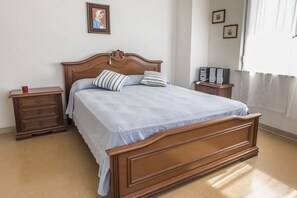 Quarto com cama de madeira, duas mesas de cabeceira e uma janela com cortinas.