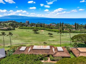 Ein Golfplatz mit Blick auf das Meer und ein Gebäude mit mehreren Dächern.