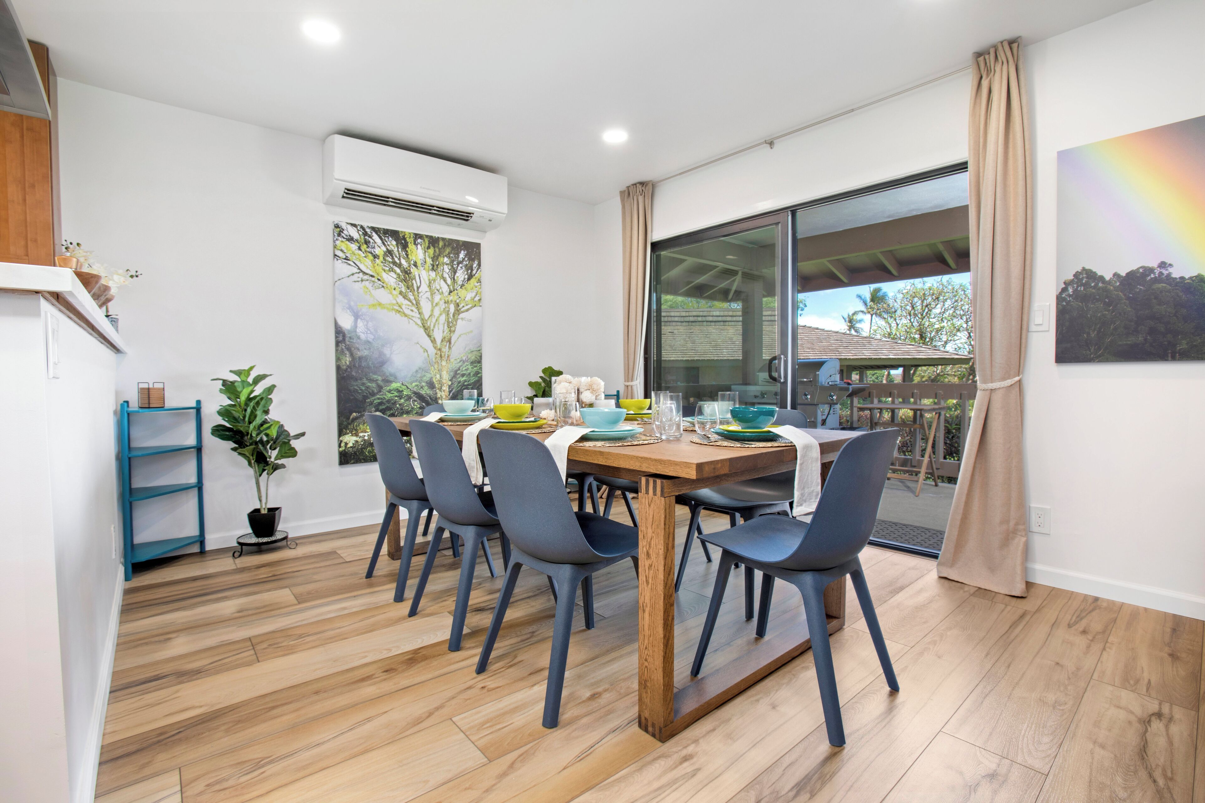 A dining area with a wooden table, blue chairs, and a view of the outdoors.