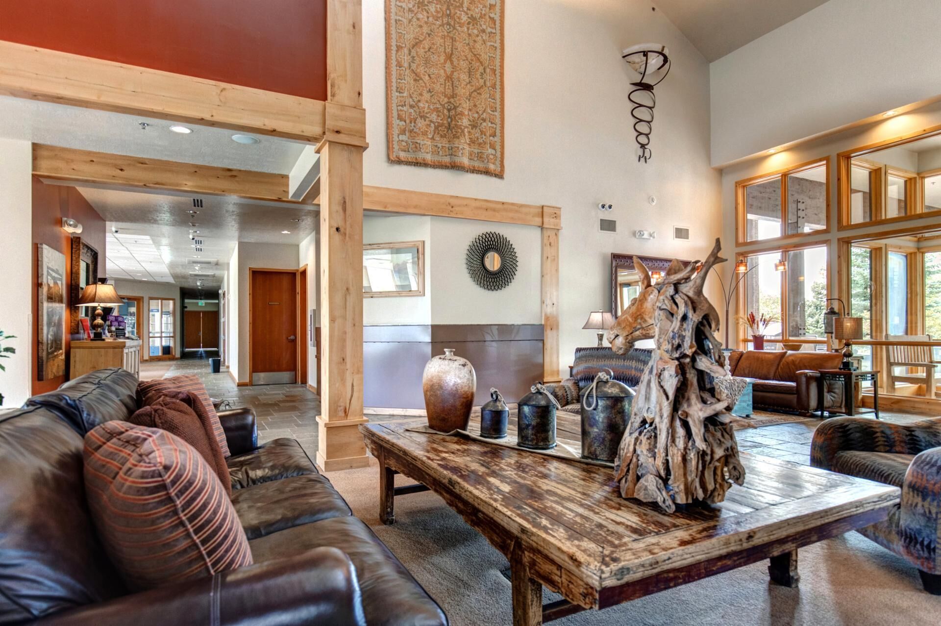 A spacious living area with a leather sofa, a wooden coffee table, and a rustic decor piece.