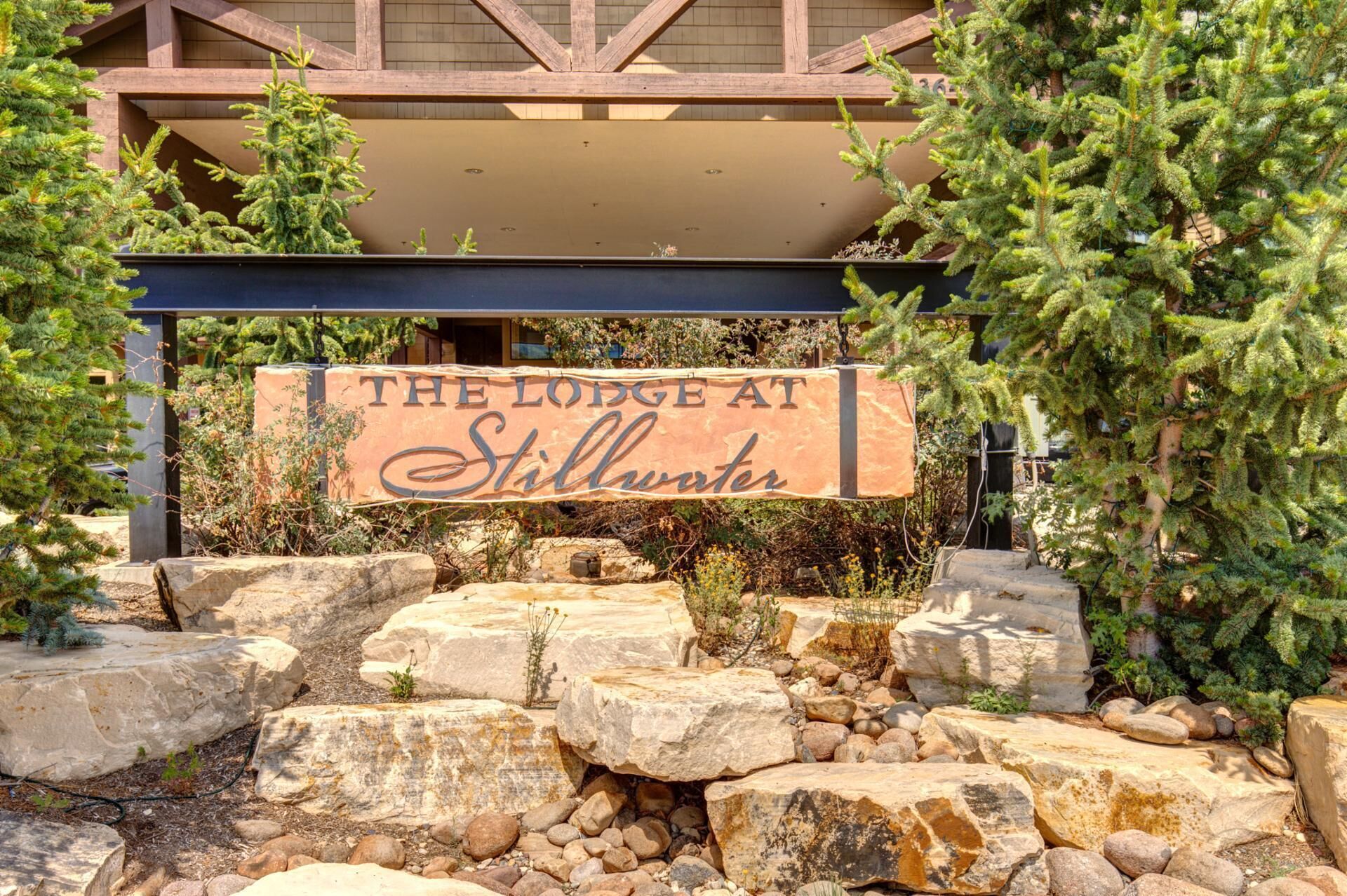 A sign for 'The Lodge at Stillwater' with a rustic stone and wooden structure in the background.