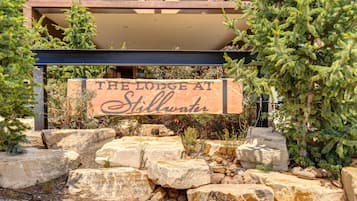 A sign for 'The Lodge at Stillwater' with a rustic stone and wooden structure in the background.