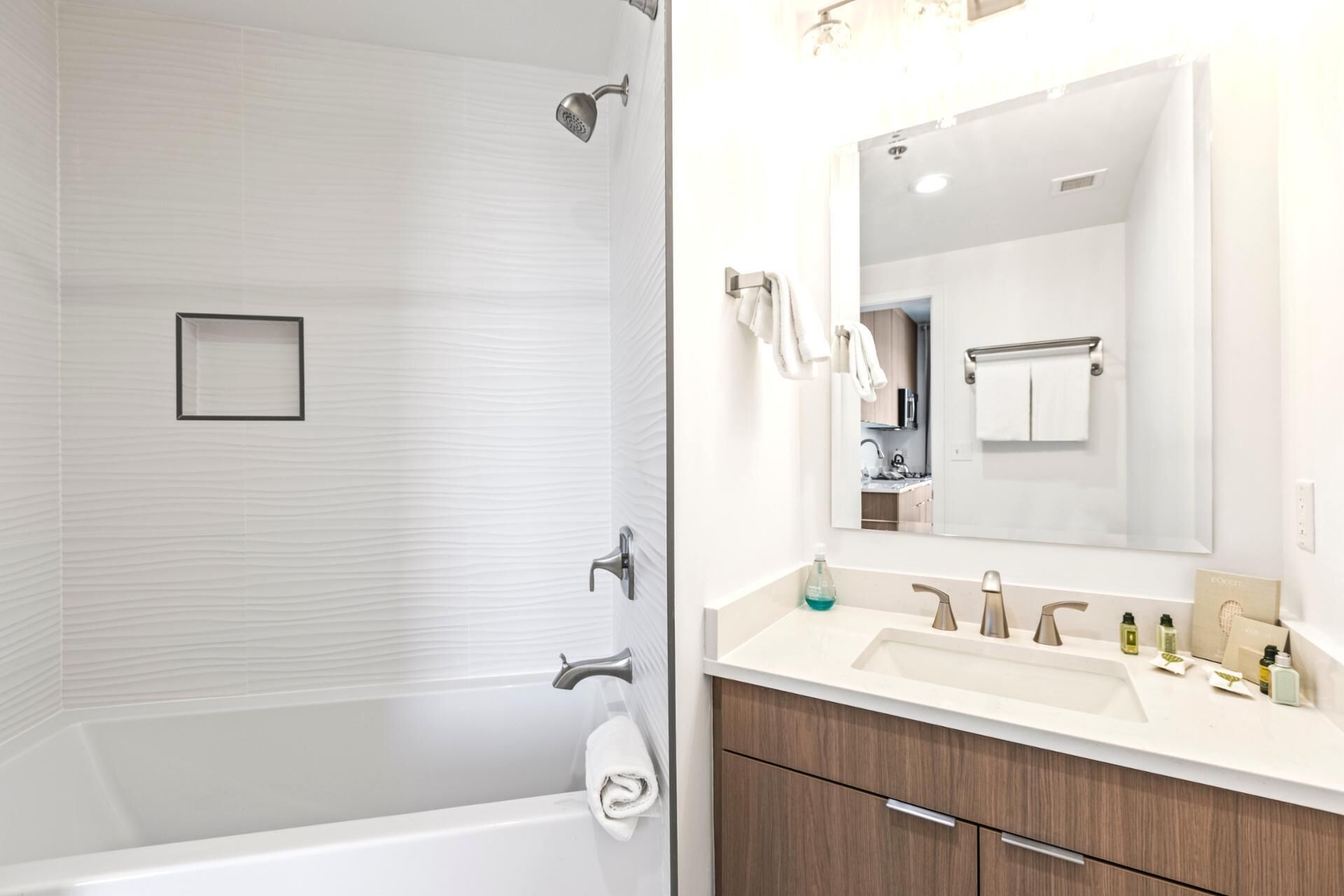 Une salle de bain moderne avec une baignoire, un grand miroir et un meuble-lavabo doté d’un évier et de plusieurs robinets.