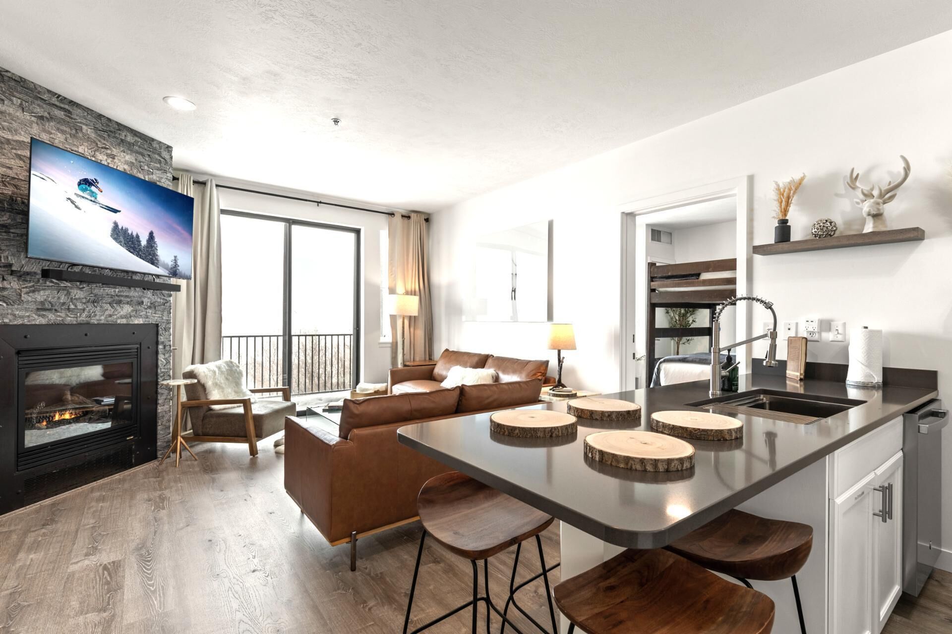 A modern living room with a fireplace, a sofa, and a dining area with stools.