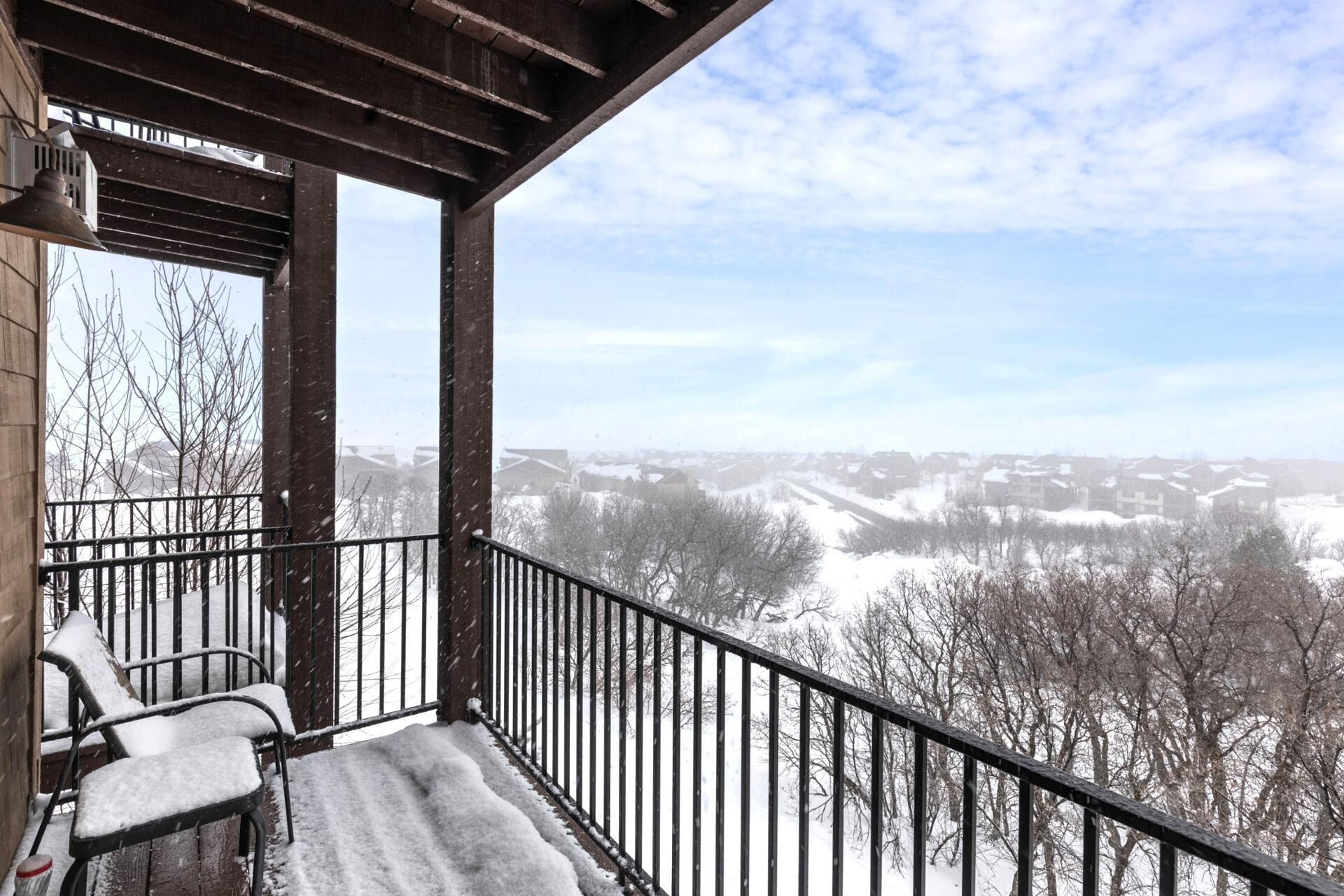 Un balcon donnant sur un paysage enneigé et des maisons.