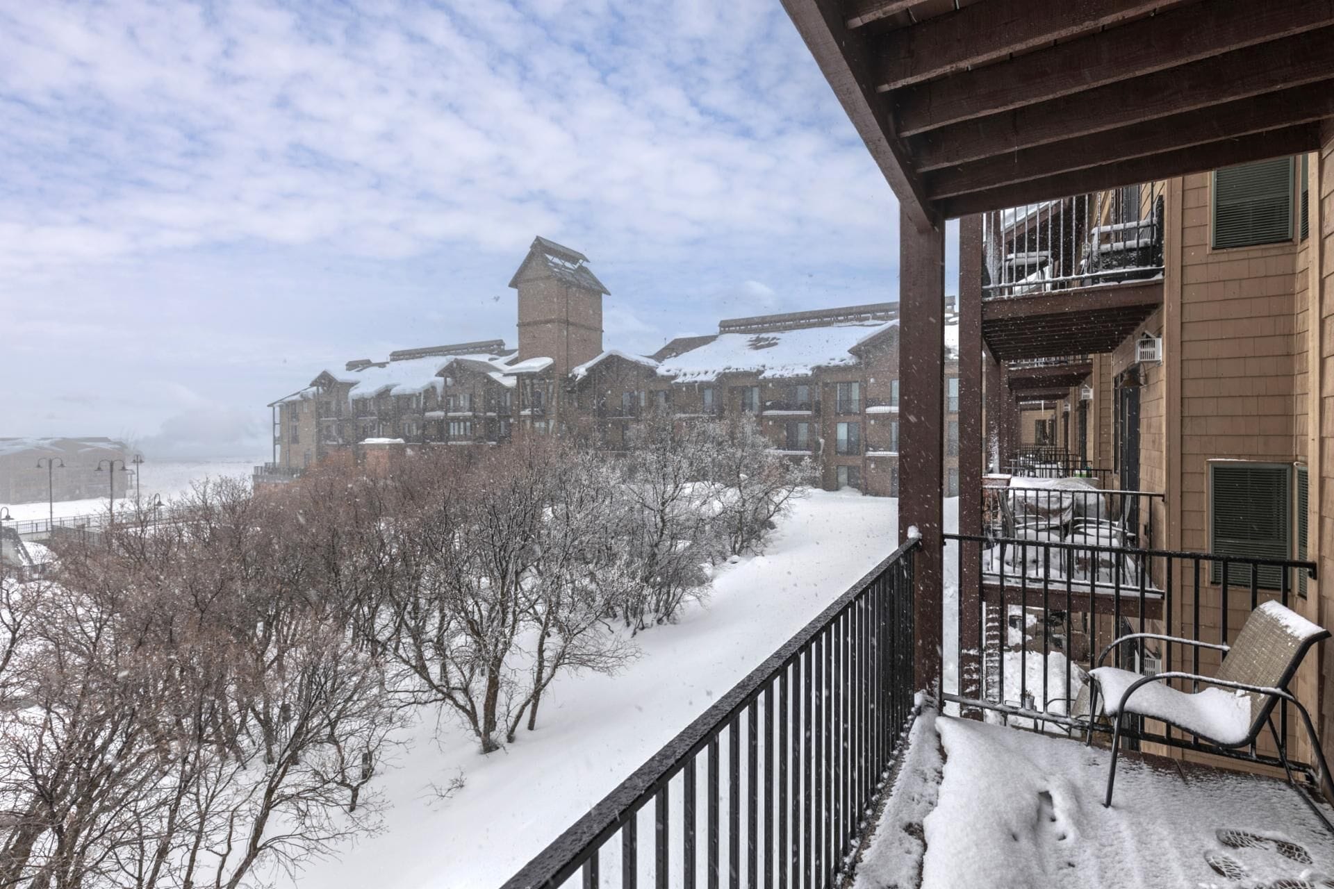 A snow-covered balcony with a view of a building with multiple windows and a tower.