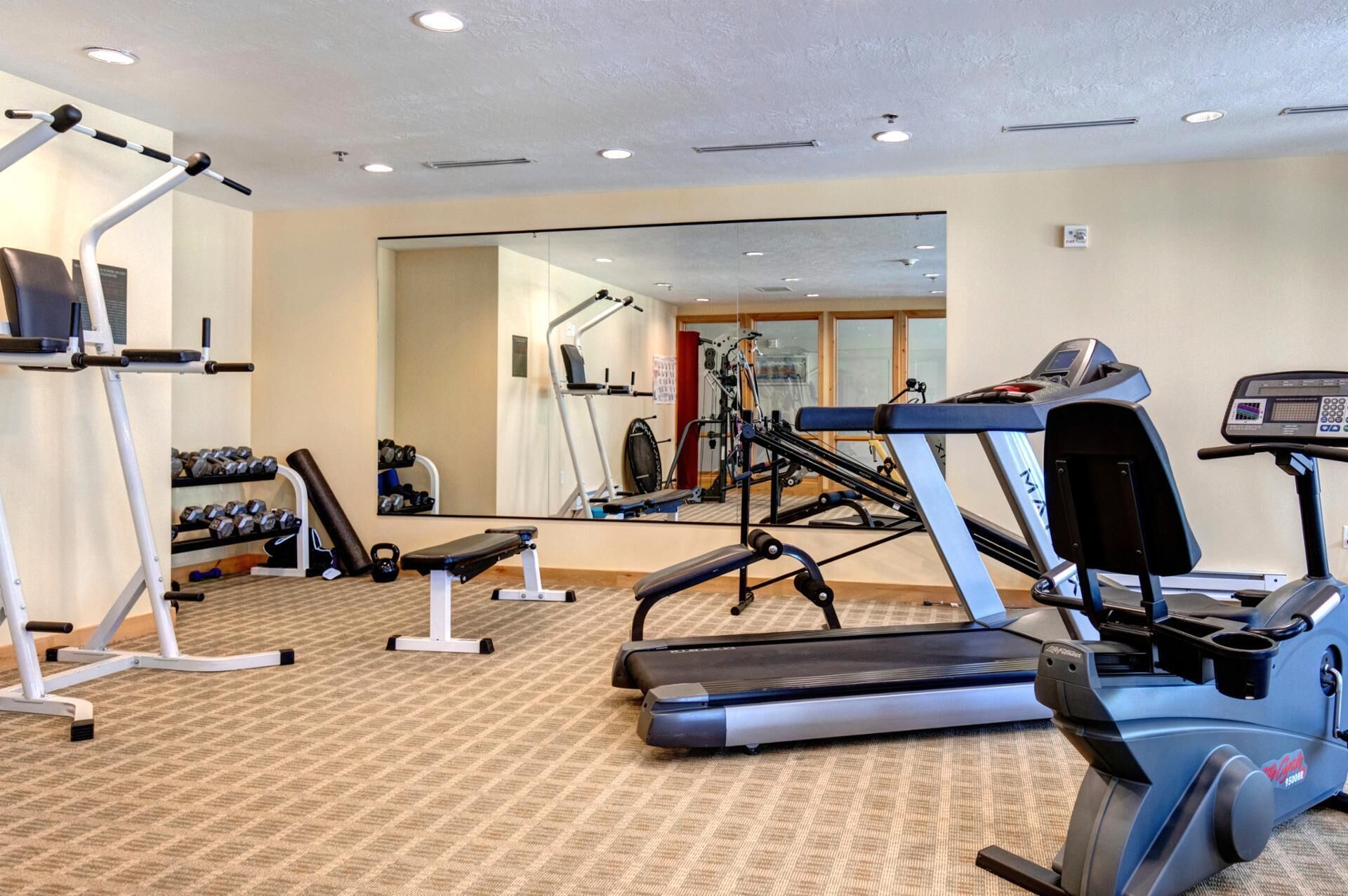 A gym with cardio equipment, weight machines, and a mirrored wall.