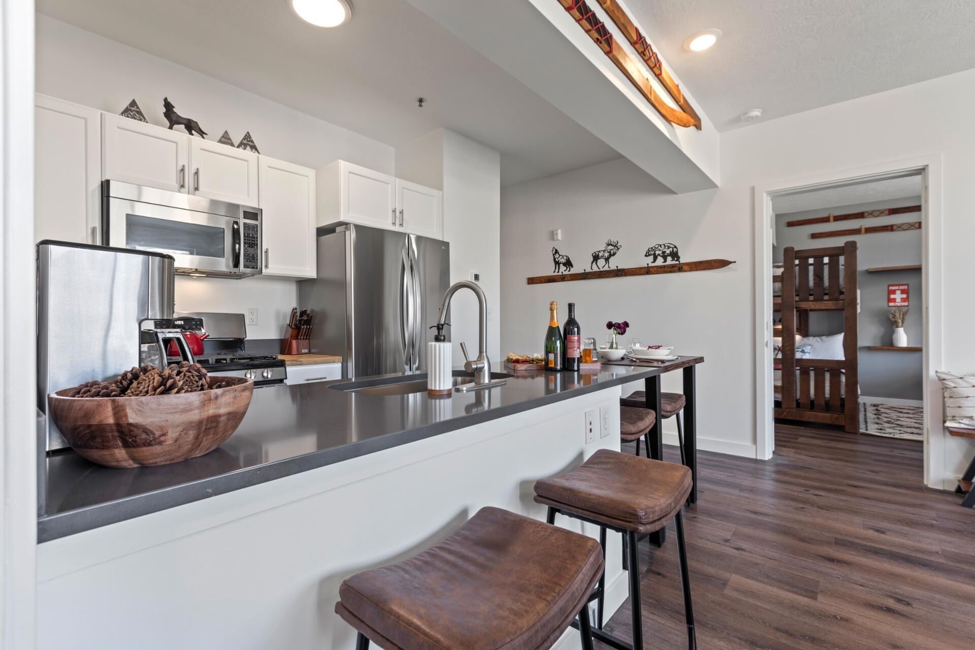 A modern kitchen with white cabinets, stainless steel appliances, and a wooden island with stools.