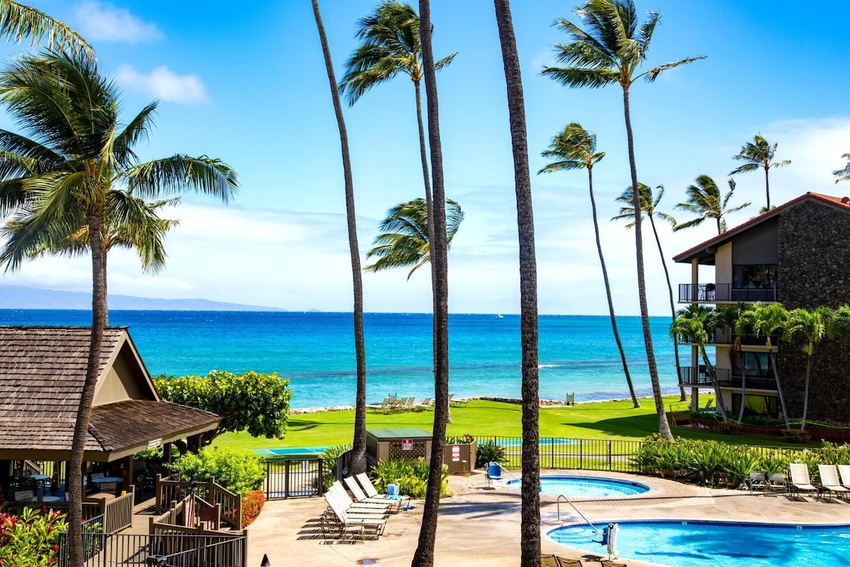 A resort with a pool, lounge chairs, and a view of the ocean.