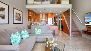 A spacious living area with a sofa, a coffee table, and a kitchen in the background. - Papakea Resort by KBM (Lahaina)