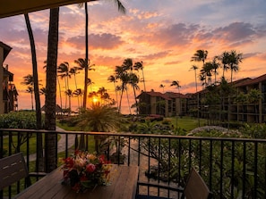A hotel with a view of the sunset, palm trees, and a pool area.