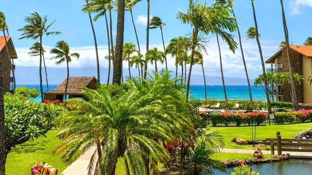 A tropical resort with palm trees, a pool, and a view of the ocean. - Papakea Resort by KBM (Lahaina)