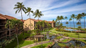A resort with multiple-story buildings, a swimming pool, palm trees, and a small pond. - Papakea Resort by KBM (Lahaina)