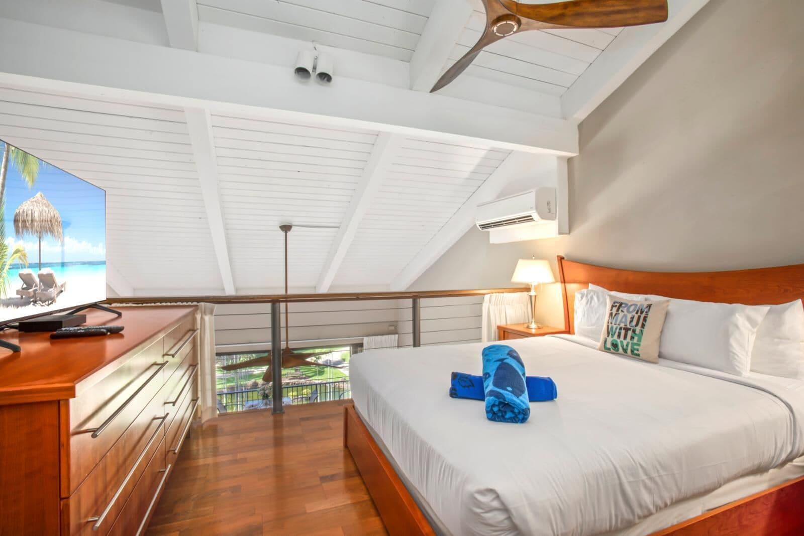 Ein Hotelzimmer mit Bett, Schreibtisch mit Fernseher, Balkon mit Aussicht und Deckenventilator.