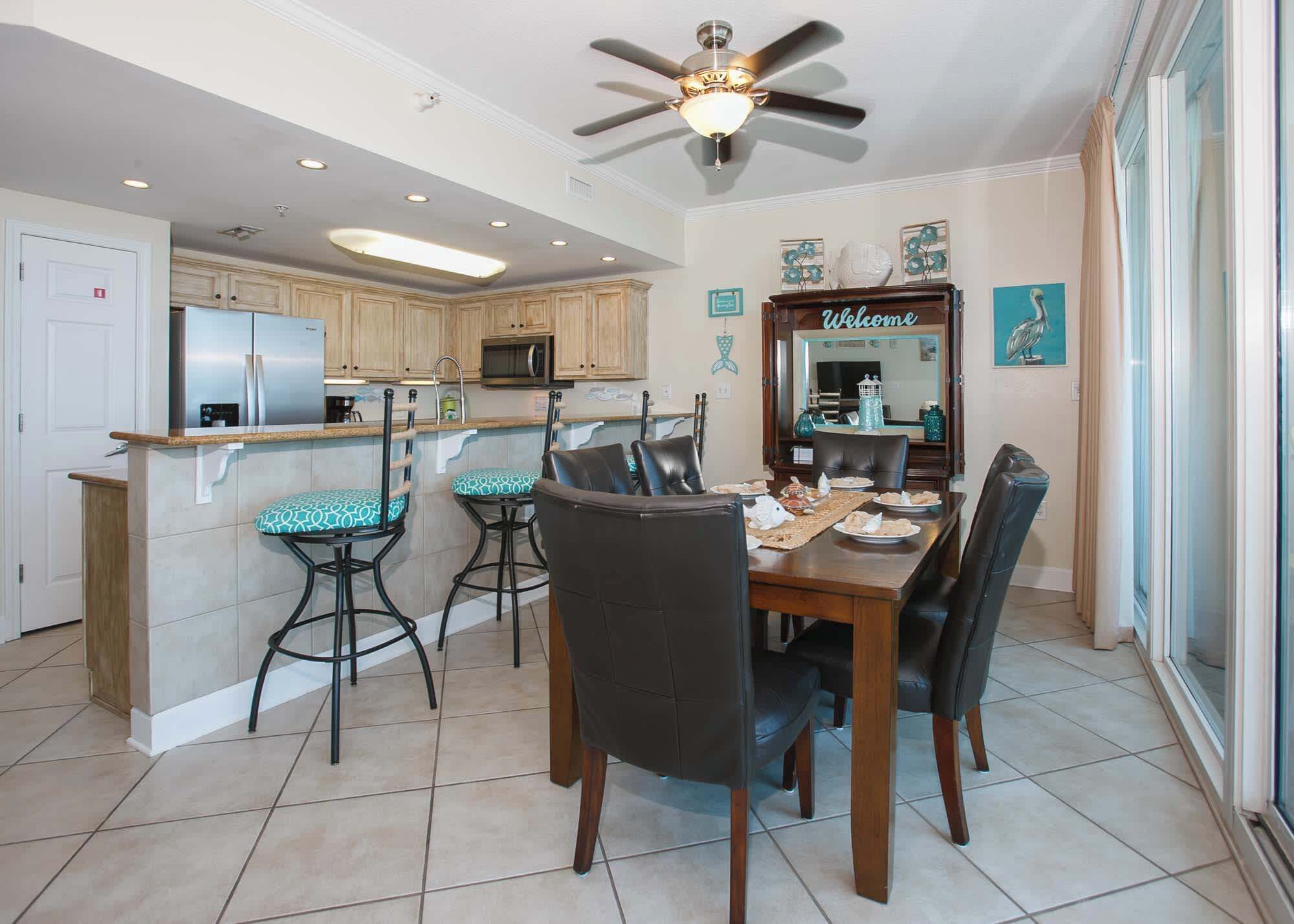 A modern kitchen with a central island, bar stools, and a dining table with chairs.