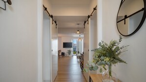 Ein Flur mit Holzboden, einem Spiegel an der Wand und einer Vase mit Blumen auf einem Tisch.