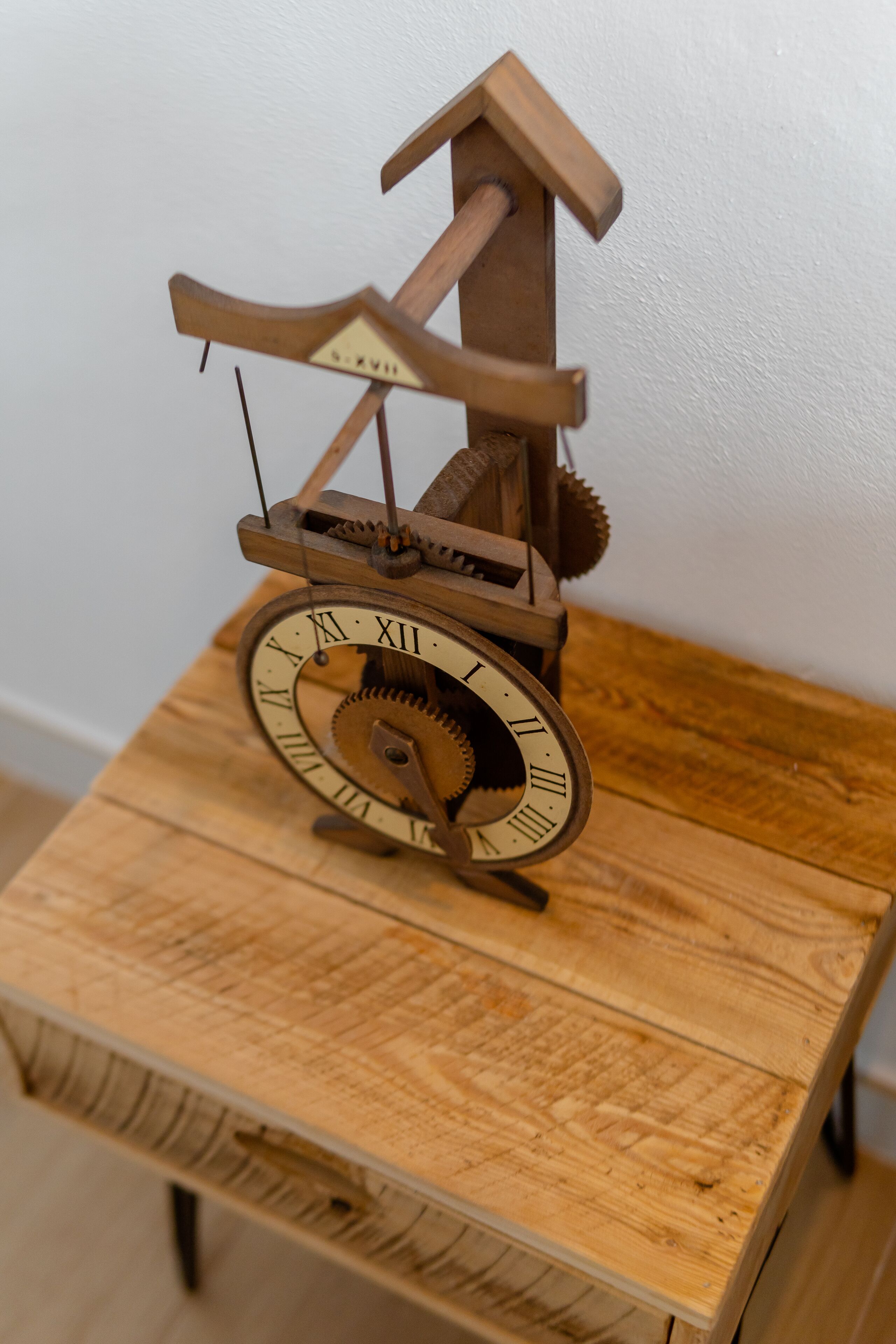 A wooden cuckoo clock with Roman numerals on its face, mounted on a wooden table.