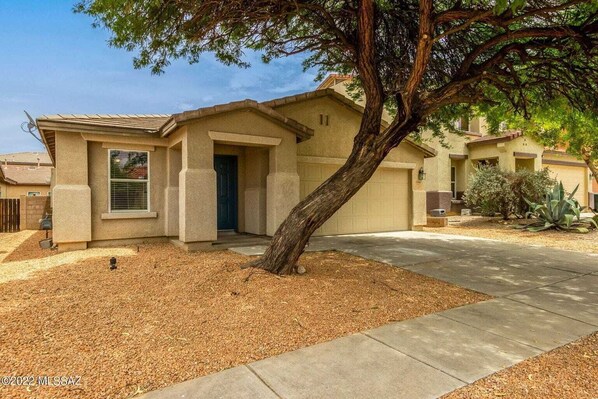 A single-story house with a garage, a front door, and a tree in the yard. - Minutes from the mountains and the Rillito River (Tucson)