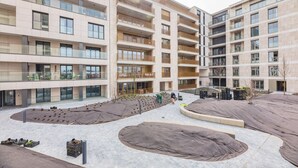 A multi-story residential building with balconies, a landscaped courtyard, and a covered outdoor area.