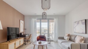 A modern living room with a TV, sofa, and a dining area with a table and chairs.