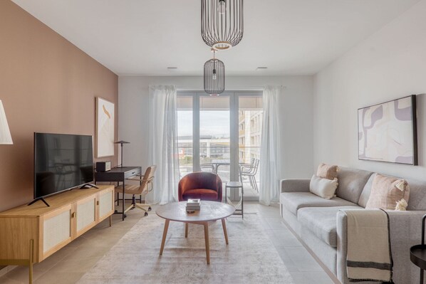 Una sala de estar moderna con televisor, sofá y comedor con mesa y sillas.