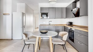 A modern kitchen with grey cabinets, a round table with chairs, and a hanging light fixture.
