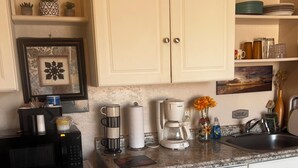 A compact kitchen with white cabinetry, a microwave, coffee maker, and a sink. - Clean, cozy studio nestled in the Grand -Staircase, near the Parks (Boulder)