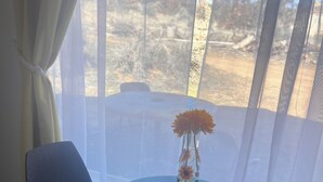 A round table with two chairs, a vase with flowers, and a window with sheer curtains. - Clean, cozy studio nestled in the Grand -Staircase, near the Parks (Boulder)