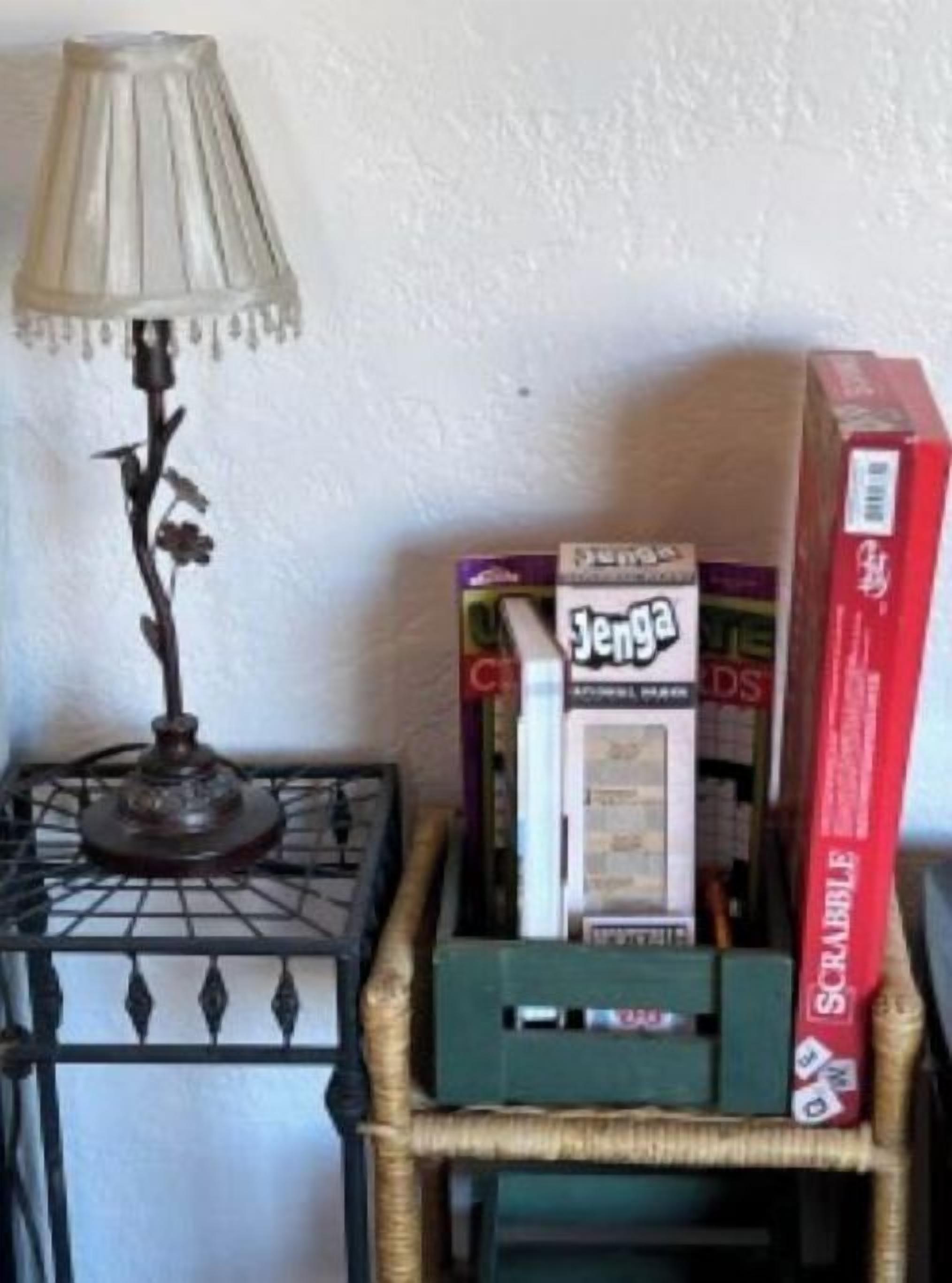 A table with a lamp, a box of Jenga, and a Scrabble box.