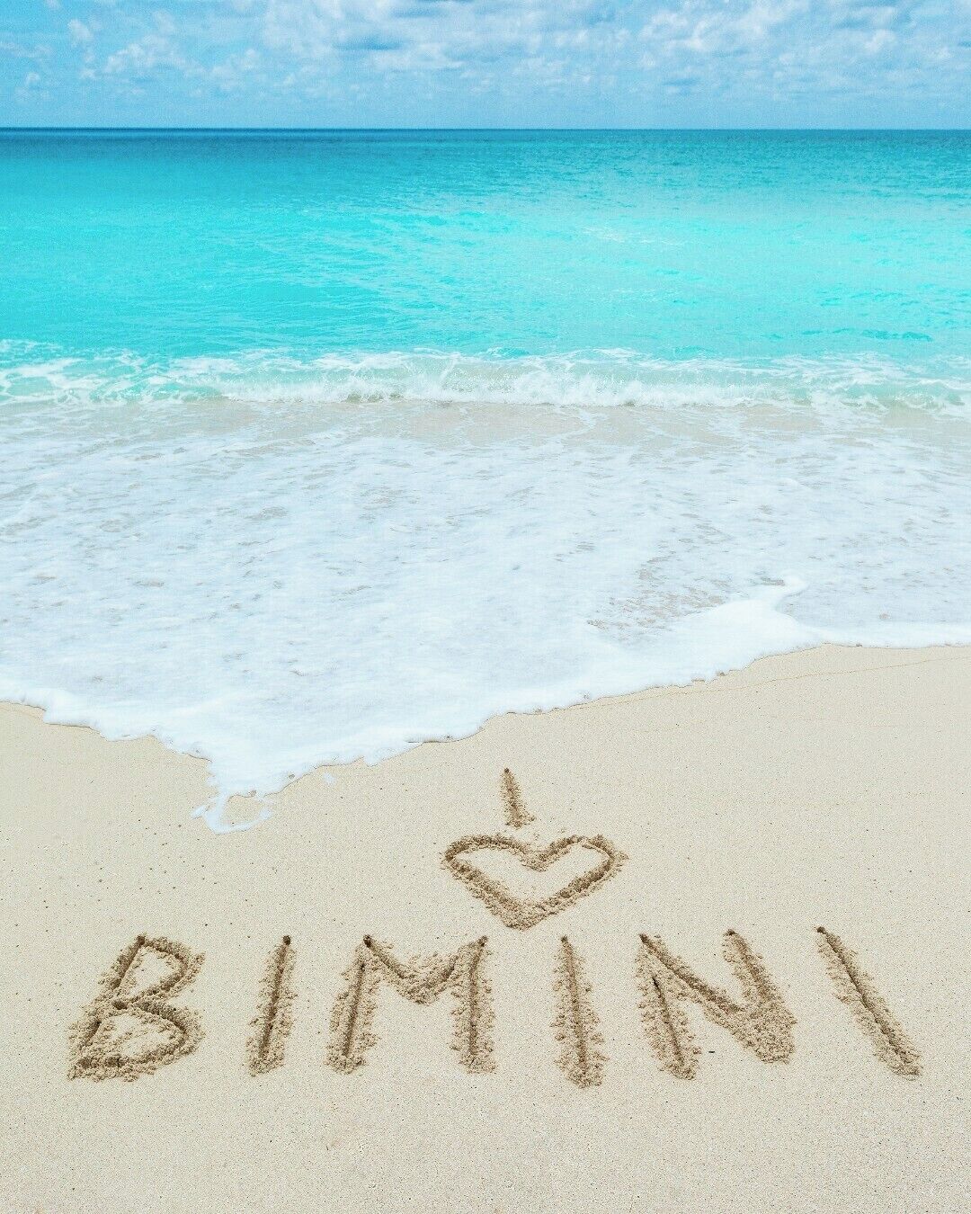 A beach with the word "BIMINI" and a heart drawn in the sand.