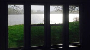 Vista a través de tres ventanas de un lago, con un área verde en primer plano.