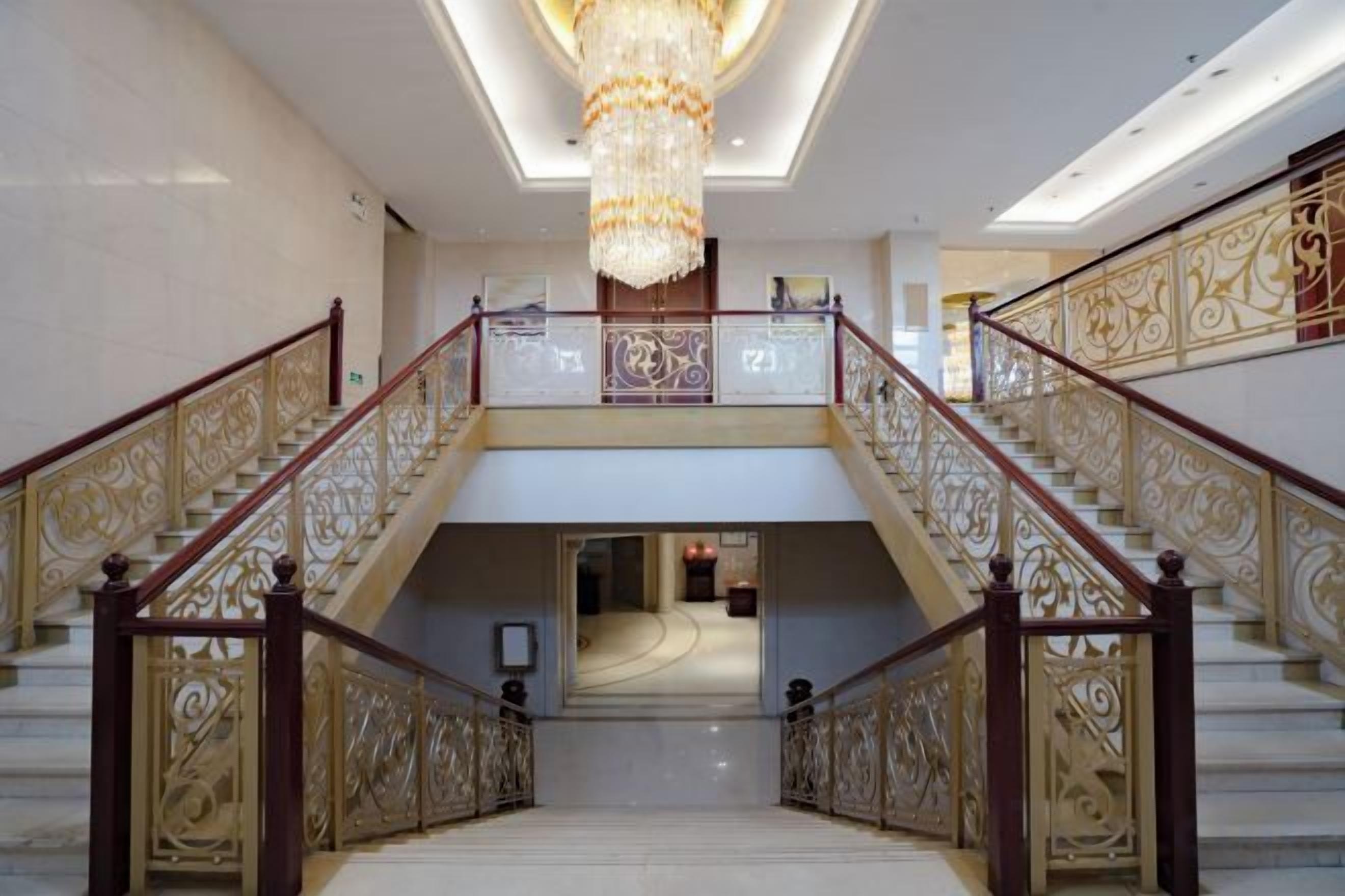 Una majestuosa escalera con barandales ornamentales y un candelabro.