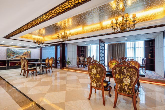 A spacious dining area with ornate chairs and chandeliers, a checkered floor, and a large window providing a view.