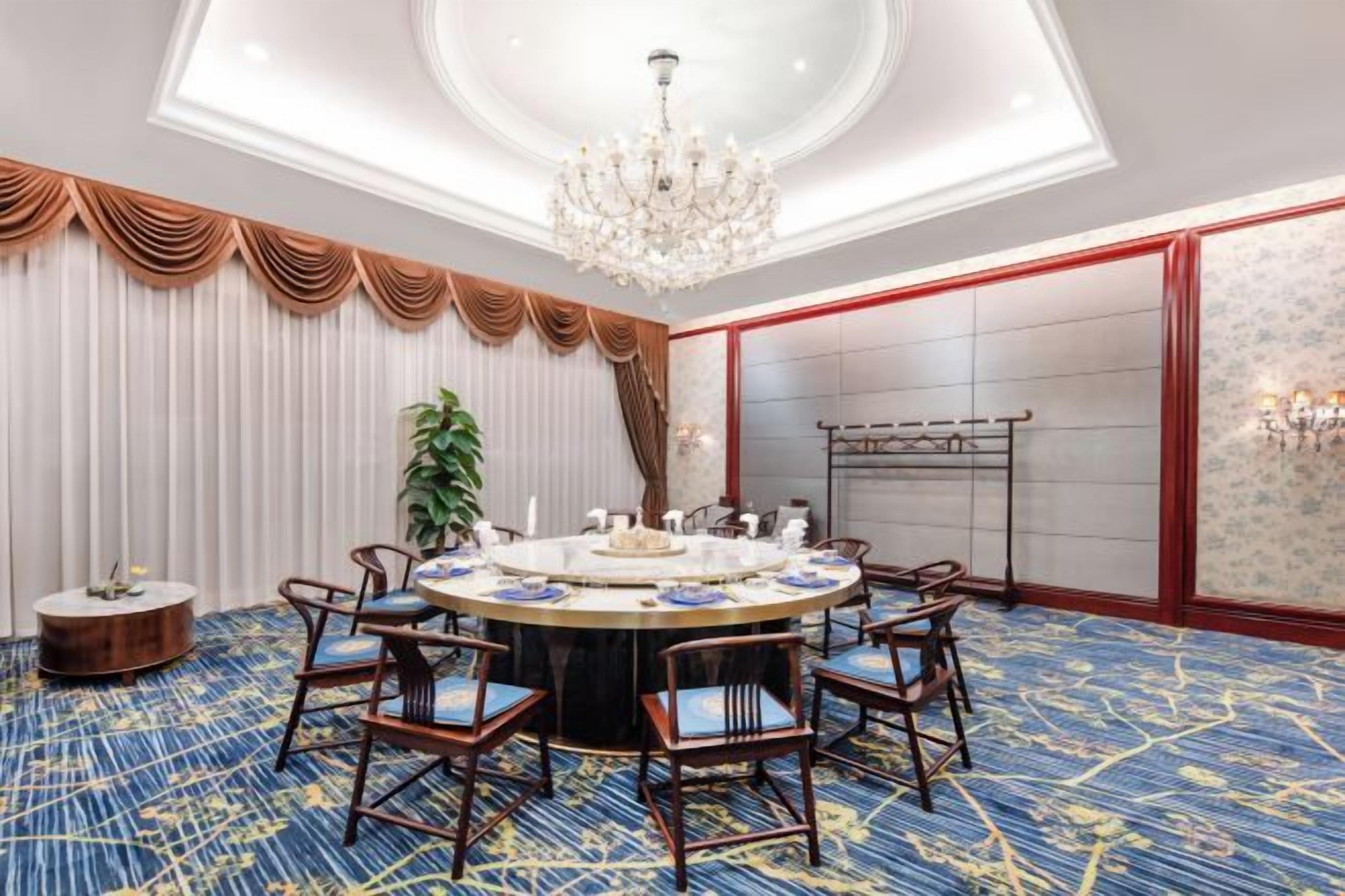 A conference room with a round table, chairs, and a chandelier.