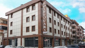 A multi-story hotel with a prominent 'HOTEL Q' sign, featuring a modern design with brown and white panels, and a visible entrance with a glass door. - Quars Garden Hotel (Düzce)
