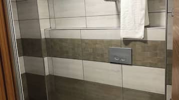 Een badkamer met toilet, een handdoekhouder met handdoek en een douchehoek.