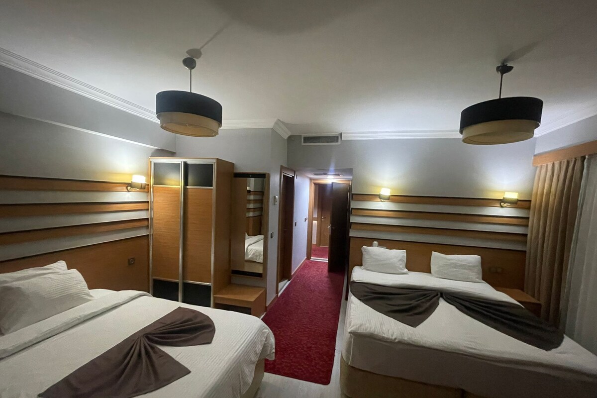 A hotel room with two beds, a wardrobe, and a mirror.