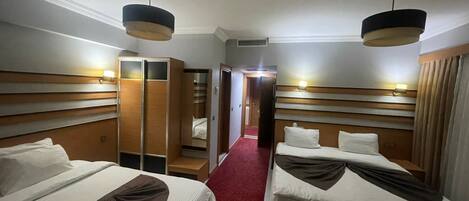 A hotel room with two beds, a wardrobe, and a mirror.