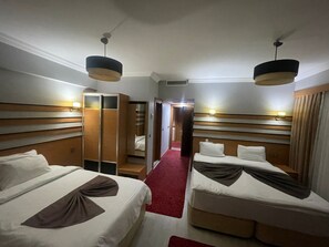 A hotel room with two beds, a wardrobe, and a mirror.