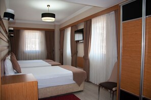 A hotel room with two beds, a TV mounted on the wall, and a chair.