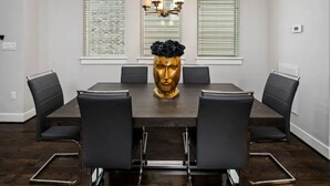 A conference room with a dark wooden table, black leather chairs, and a gold decorative centerpiece. - Centrally Located--Alluring Townhome w/ Engaging Decor & Beautiful Skyline Views (Houston)