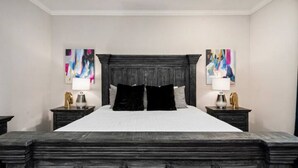 A bedroom with a large bed, two nightstands, and abstract wall art. - Centrally Located--Alluring Townhome w/ Engaging Decor & Beautiful Skyline Views (Houston)