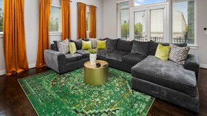 A living room with a sectional sofa, a round coffee table, and a patterned rug. - Centrally Located--Alluring Townhome w/ Engaging Decor & Beautiful Skyline Views (Houston)